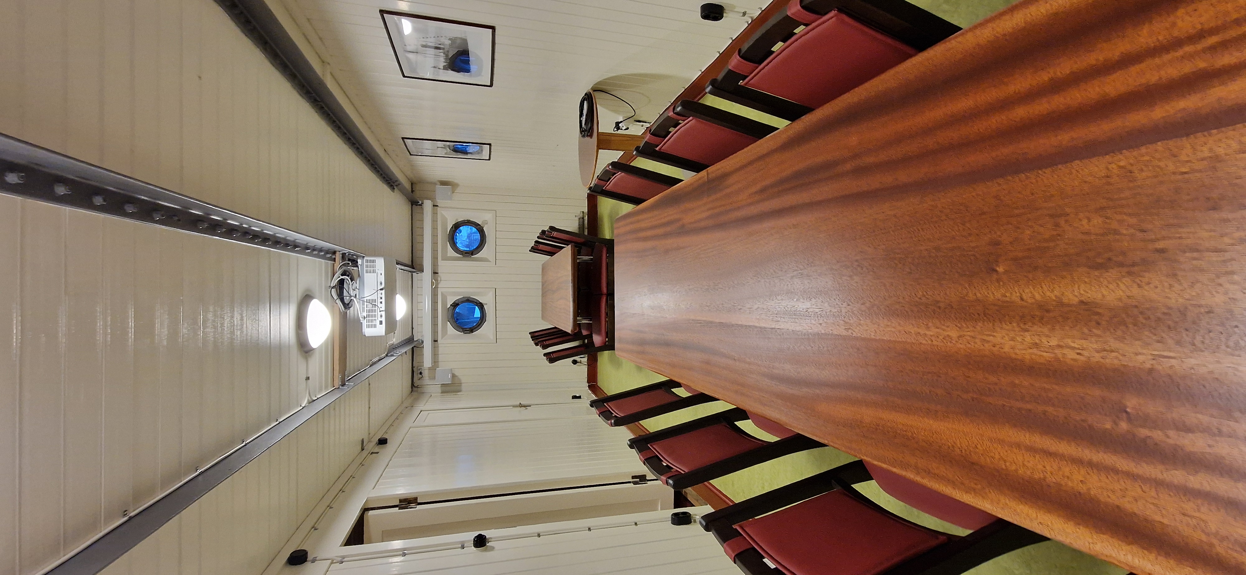 Ett mötesrum med träbord och 16 stolar. Med projektor