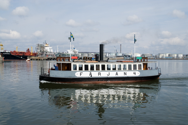 Färjan fyra är en ångfärja med svart skrov samt grå- och vitmålad överbyggnad i ett plan. I både för och akter finns styrhytter och landgångar. Midskepps syns även en svart skorsten. Längs långsidan står fartygsnamnet målat i svart. På bilden går Färjan fyra på Göta älv i centrala Göteborg. 