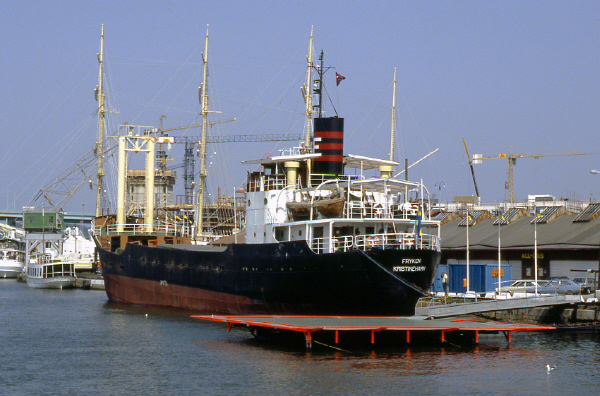 Fryken är ett lastfartyg med svart skrov. I aktern finns en överbyggnad i tre våningar med kommandobryggan och en svartröd skorsten. Midskepps och föröver finns lastutrymmen. På bilden ligger Fryken i Göteborgs hamn med hamnskjul och en äldre hamnkran i bakgrunden. 