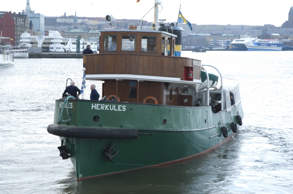 Herkules är en bogserbåt med högt grönt skrov och gummiskoning i fören. Överbyggnaden är i två våningar och styrhytten har tre framrutor. Överbyggnaden är klädd i brunt trä. På bilden är Herkules ute på Göta älv i Göteborgs hamn, till höger skymtar man Masthuggskyrkan.