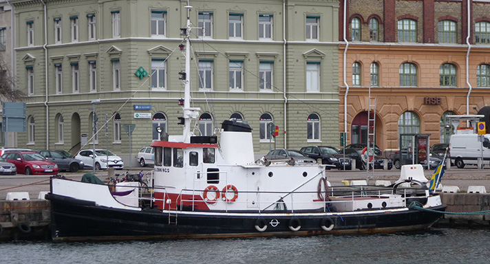 Fartyget John Jennings har svart skrov och en vit överbyggnad med styrhytt. Hon har en liten mast med lanternor ovanpå styrhytten och bakom syns en vit skorsten. På bilden ligger John Jennings vid Tullhamnens kaj i Kalmar. 