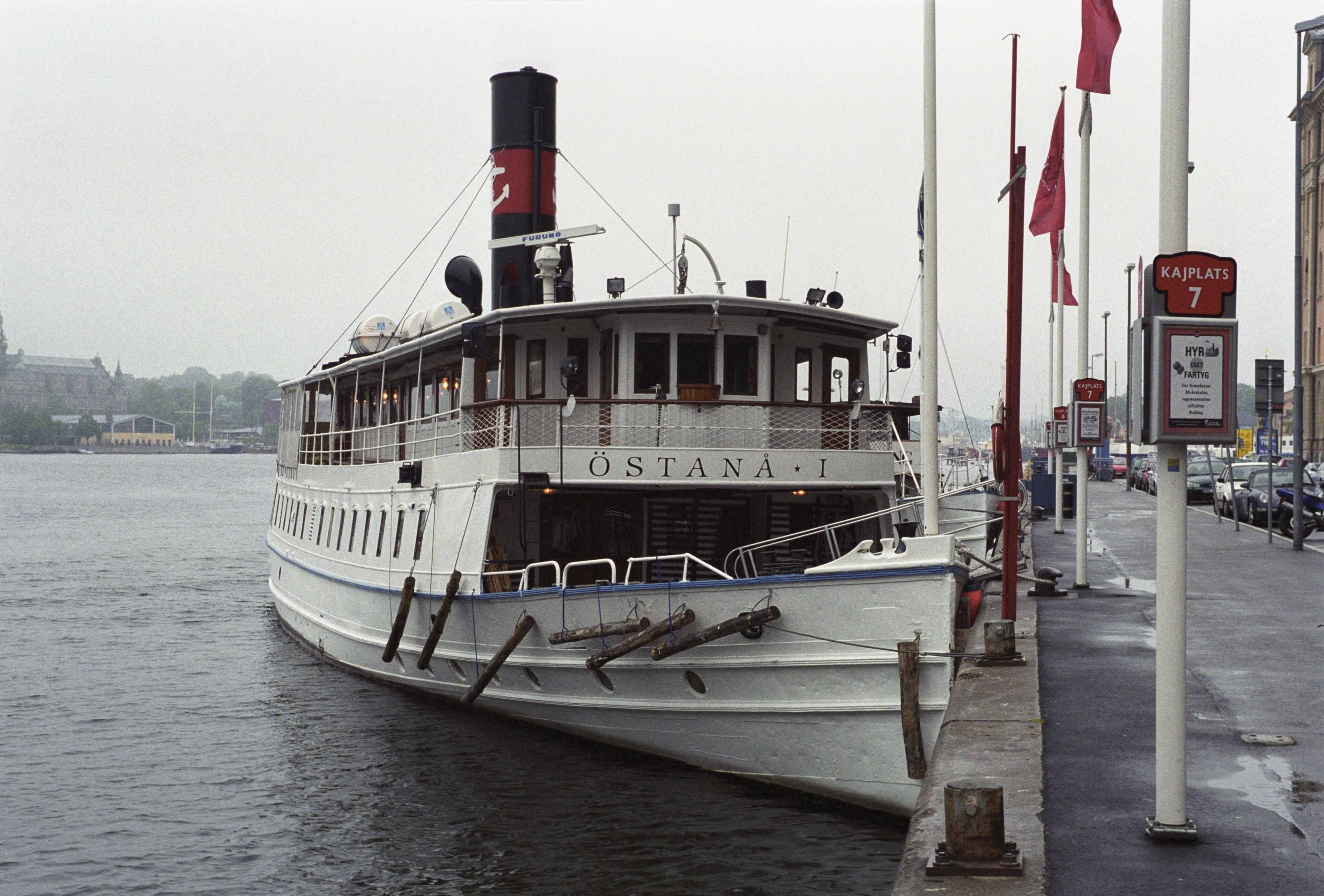 Östanå ett är ett vitmålat passagerarfartyg med salonger på två däck. Hon har landgången utfälld från fördäck till kajen. Midskepps syns en skorsten med rött emblem med ett vitt ankare. Fartyget ligger förtöjt vid Nybroviken i Stockholm. 
