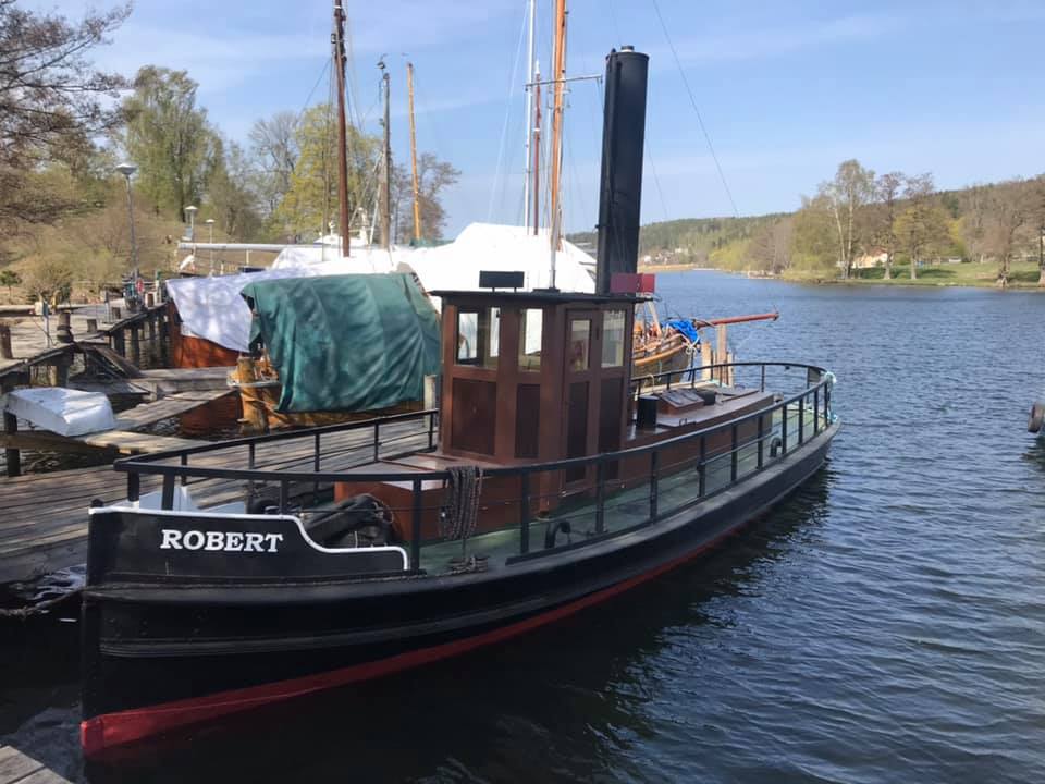 Robert är en mindre svartmålad bogserbåt med styrhytt och hög skorsten midskepps. Det går att gå runt hela båten längs ett svart stålräcke. På bilden ligger båten förtöjd vid en brygga.