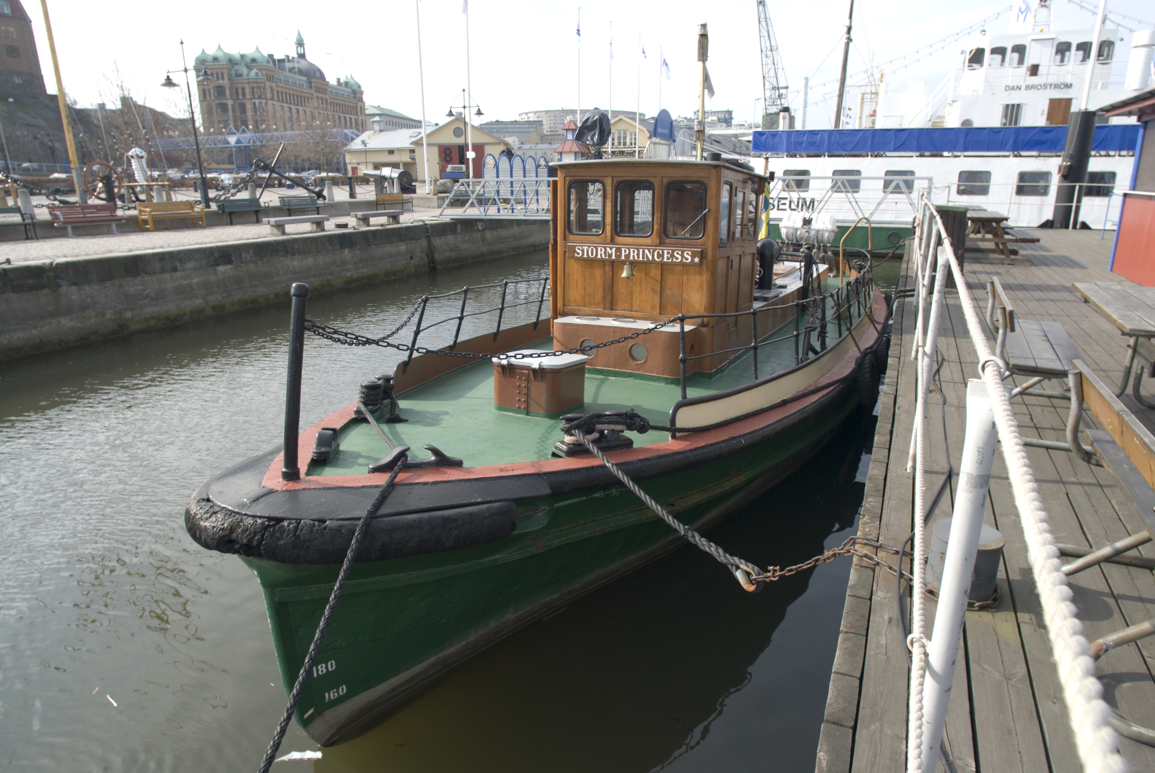 Storm Princess är en bogserbåt med svart skrov, grönt däck och en styrhytt i ljusbrunt trä midskepps. På bilden ligger fartyget förtöjt vid en kaj i centrala Göteborg. 