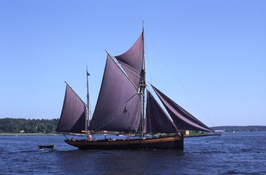 Sunbeam är en ketch, ett segelfartyg med mörkblå lila segel. På bilden är alla segel satta eftersom fartyget är ute till sjöss. Skrovets för är lodrätt medan aktern har en rundare profil. På släp har fartyget sin jolle. 