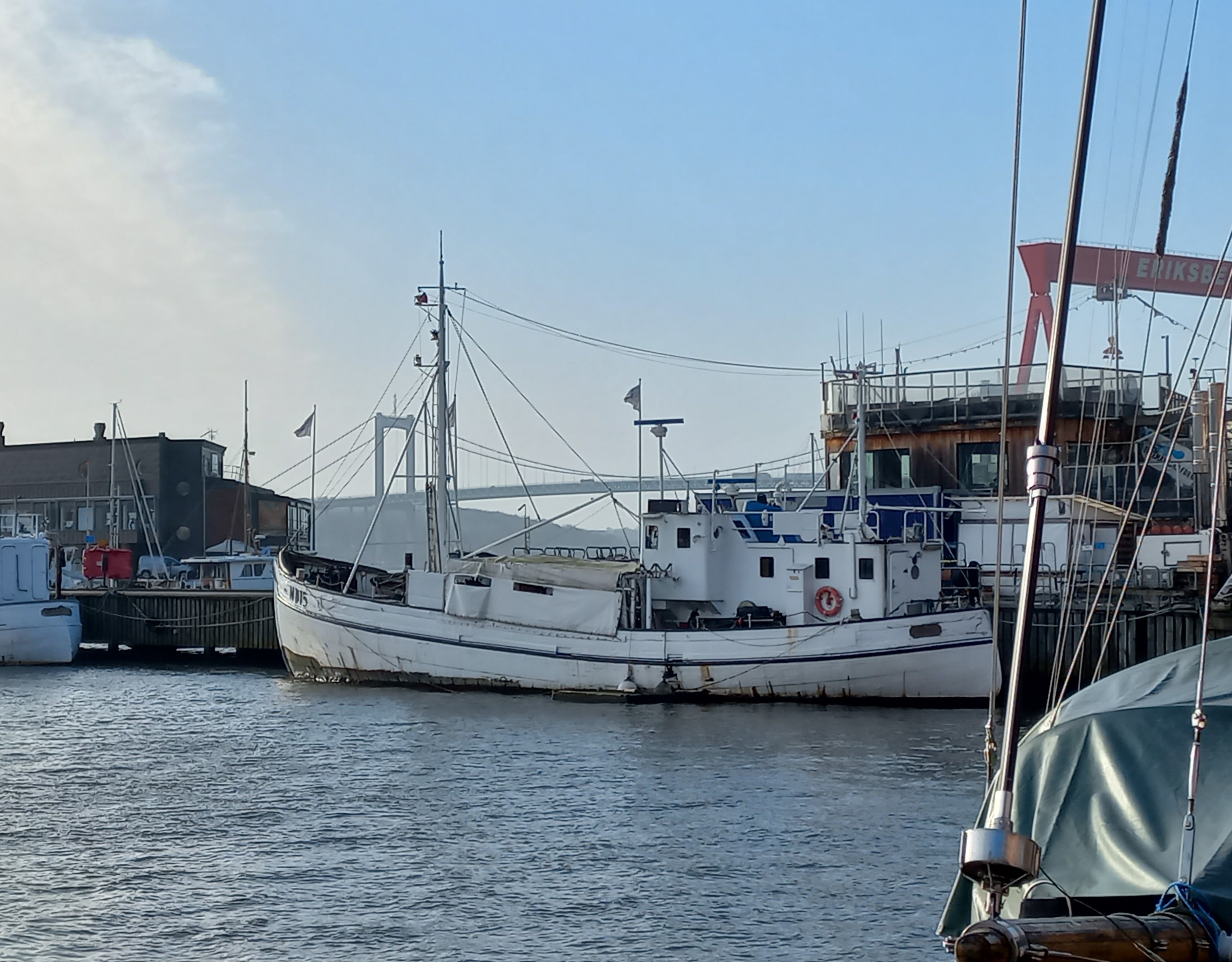Svanen West är ett vitmålat fiskefartyg med mast och lastningsutrymmen i fören och styrhytt och övriga utrymmen i aktern. På bilden ligger båten vid kaj i Eriksbergshamnen i Göteborg. 