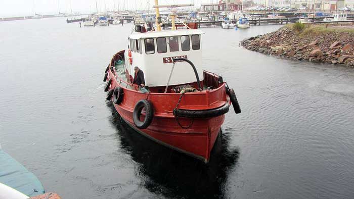 Sven är en bogserbåt med rött skrov, grönt däck och en vit styrhytt midskepps. Längs med skrovet hänger bildäck som fendrar. På bilden är fartyget på väg in i en hamn. 