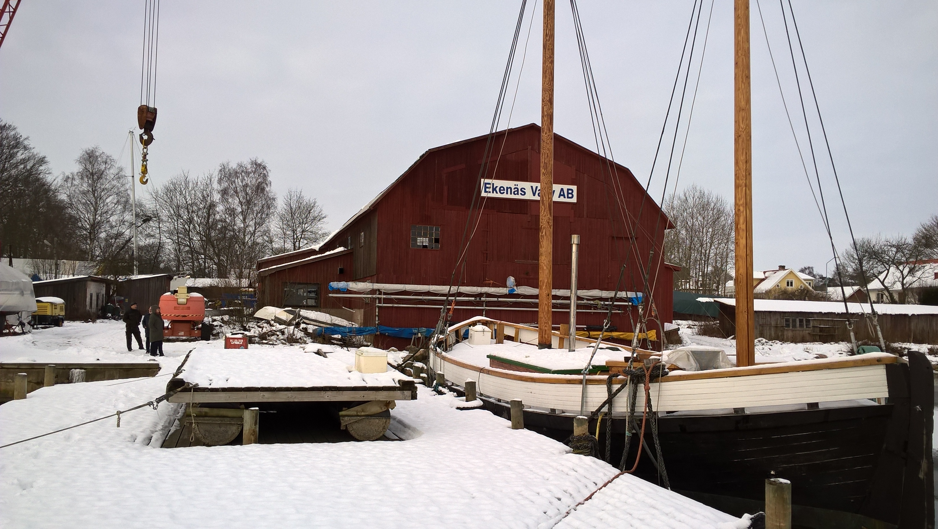 Pamela är ett tvåmastat segelfartyg som ligger förtöjt vid en kaj. Övre delen av skrovet är vitmålat och hon har ett täcke av snö på däck. På bilden syns det stora rödfärgade skeppsskjulet i Ekenäs utanför Kalmar i bakgrunden. 