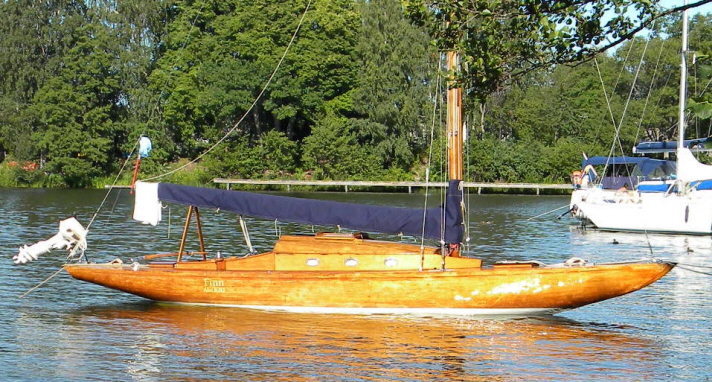 Finn är en segelbåt i hondurasmahogny med utombordaren uppdragen i aktern. Eftersom båten inte är målad är träet synligt i skrov, däck och överbyggnad. Hon har tre ventiler i ruffen och sittbrunn i aktern. Hon ligger förtöjd vid en brygga.