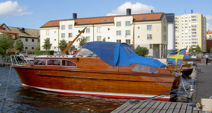Florida är en motorkryssare i mahogny med stor ruff med stora fönsterventiler. I aktern har hon styrhytten med ett beige kapell med akterbågar. Båten ligger i en småbåtshamn på bilden. 