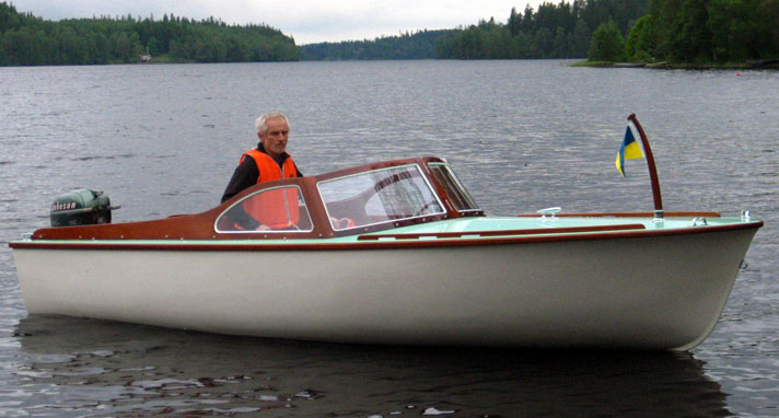 Iris är en liten sportbåt med vitt plastskrov samt turkosblått ldäck. Bakom vindrutan syns en man i flytväst. 