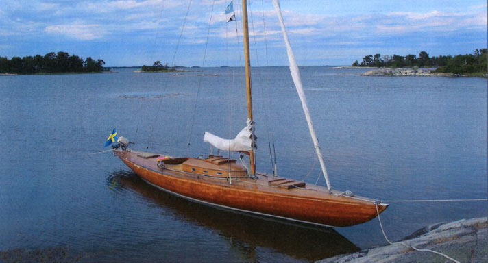 Taifun är en skärgårdskryssare i mahogny. Hon har en ruff midskepps och en liten sittbrunn bakom. Seglen är revade och hon ligger för ankare vid några klippor.