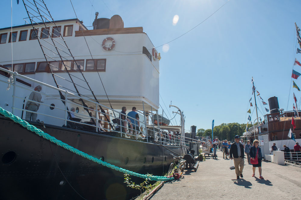 Museifartygspiren en sommardag. Ett flertal personer går på piren. Vid piren ligger Isbrytaren Sankt Erik.